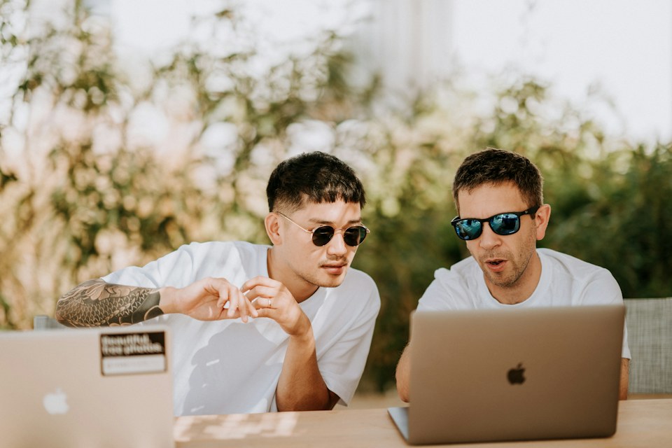 Two colleagues talking across a table with their laptops